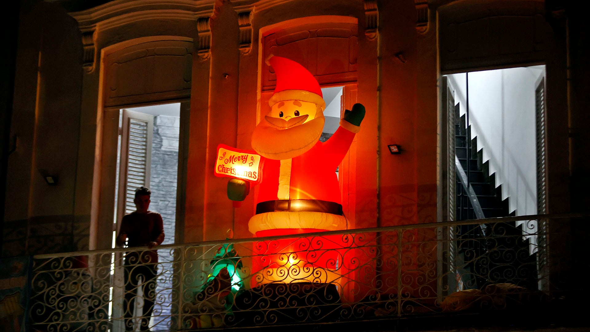 Una persona descansa en un balcón con adornos de Navidad (EFE/Ernesto Mastrascusa)