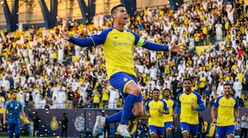 El futbolista Cristiano Ronaldo salta y grita de celebración con los brazos extendidos, vistiendo un uniforme amarillo y azul, frente a una multitud difusa en un estadio.