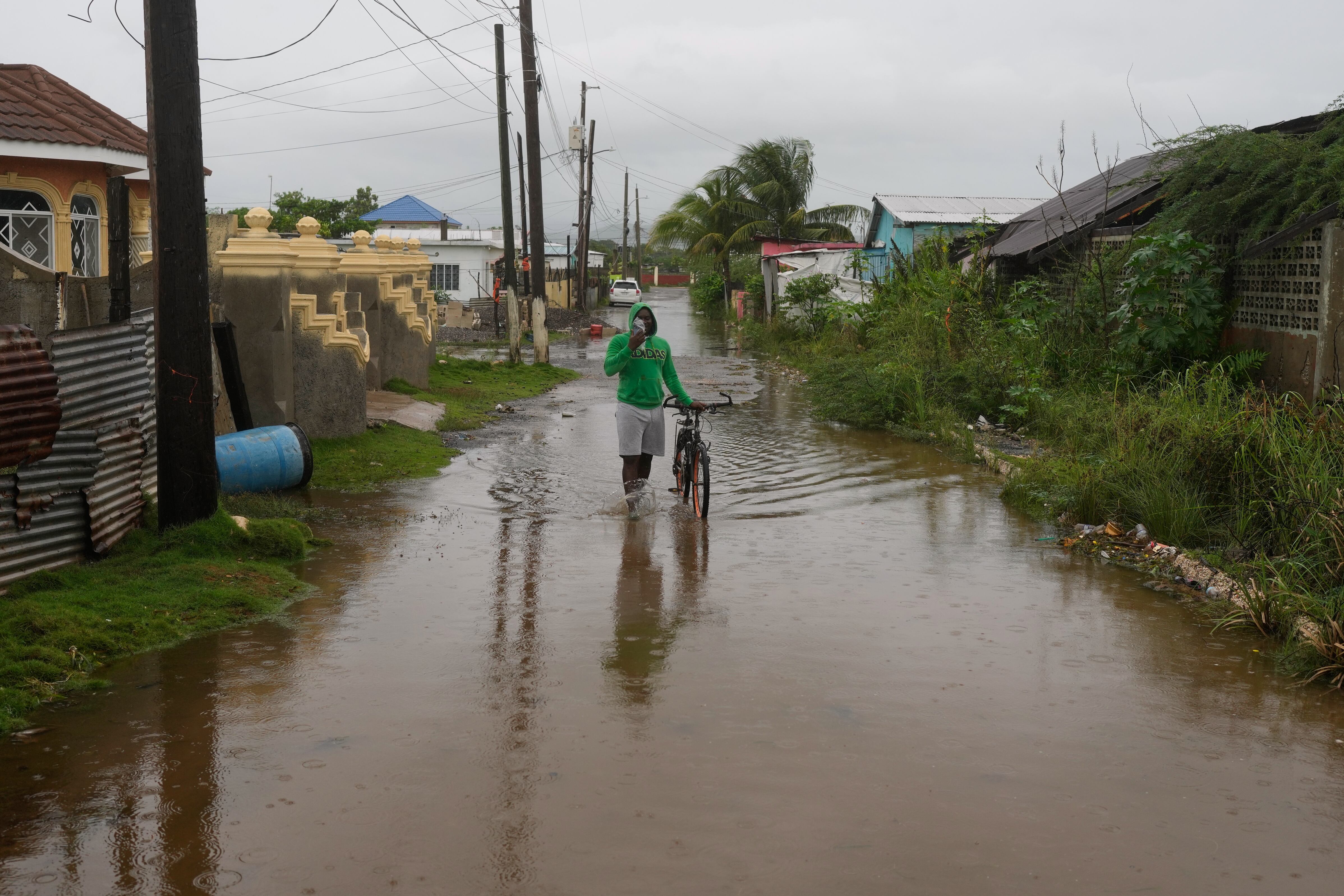 Un hombre camina por una calle inundada antes de la llegada del huracán Melissa, el lunes 27 de octubre de 2025, a Old Harbour, Jamaica. (AP Foto/Matías Delacroix)