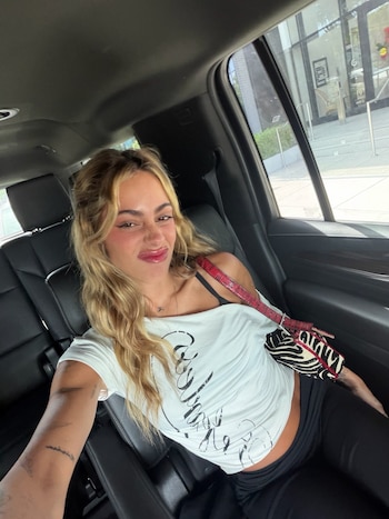 De vuelta en el asiento trasero de un auto, Stoessel cambió de look: remera blanca con inscripción en letras cursivas y cartera cebra con correa roja