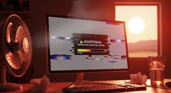 Monitor de computadora glitcheado mostrando alerta de temperatura crítica, humo, ventilador, teclado y vaso de agua en un escritorio.