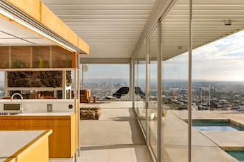 Una cocina de madera y una sala de estar separadas por paredes de vidrio de una piscina y una vista panorámica de la ciudad
