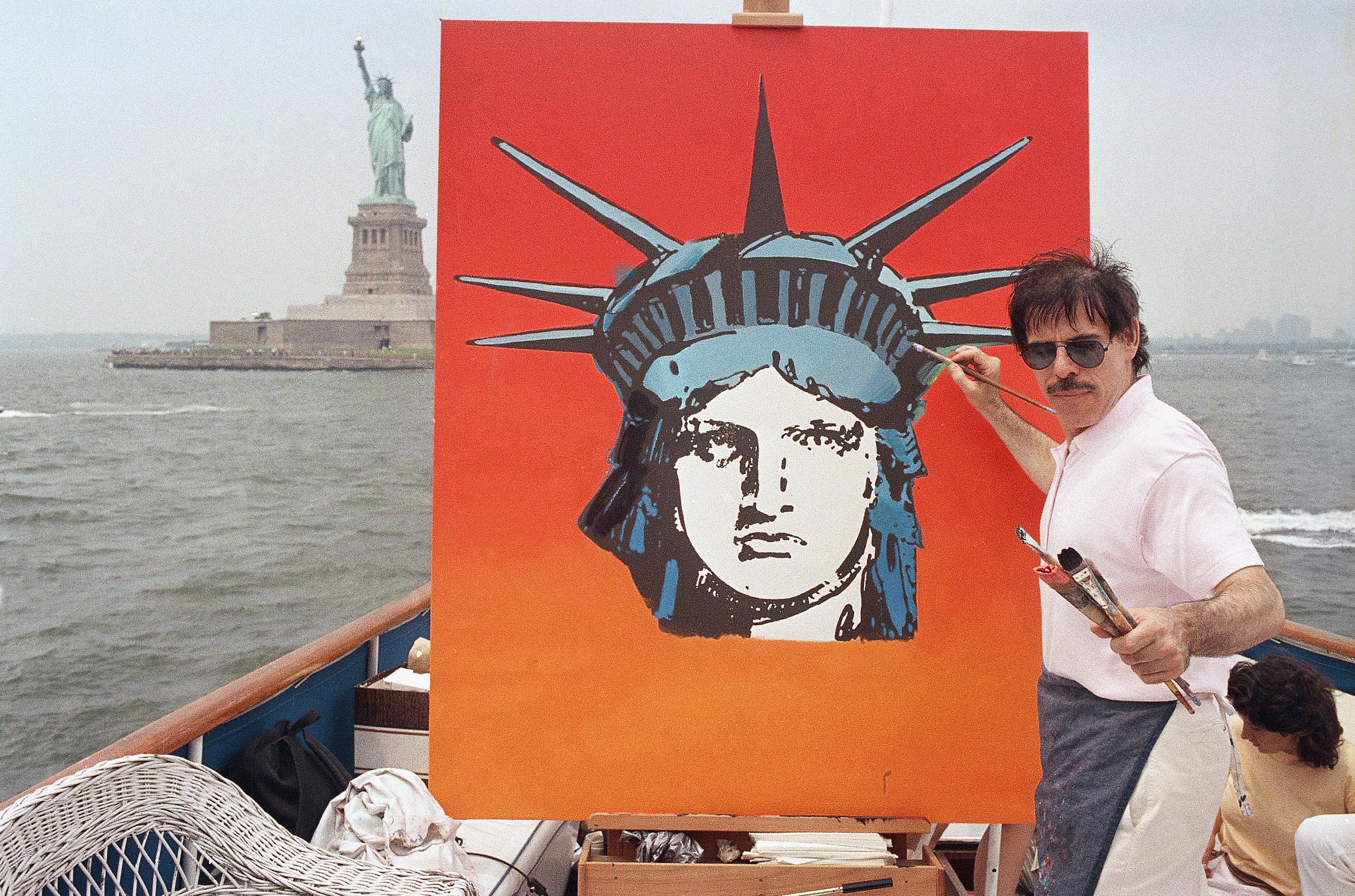 El artista Peter Max trabaja en una pintura de la Estatua de la Libertad a bordo de un barco en el puerto de Nueva York, el 4 de julio de 1987, en Nueva York (AP/David Bookstaver)