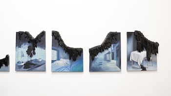 Cuatro cuadros rectangulares colgados en fila sobre una pared blanca muestran escenas de habitaciones azules con una sustancia negra brillante encima