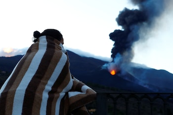 Una mujer envuelta en una manta observa el volcán de La Palma, el 28 de octubre de 2021. (REUTERS/Borja Suarez)
