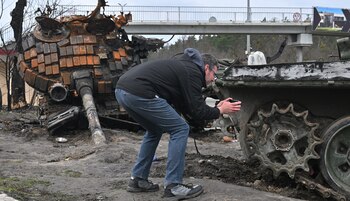 A residents takes a picture of a destroyed Russian tank on the outskirts of Buzova village, west of Kyiv, on April 10, 2020. (Photo by Sergei SUPINSKY / AFP)