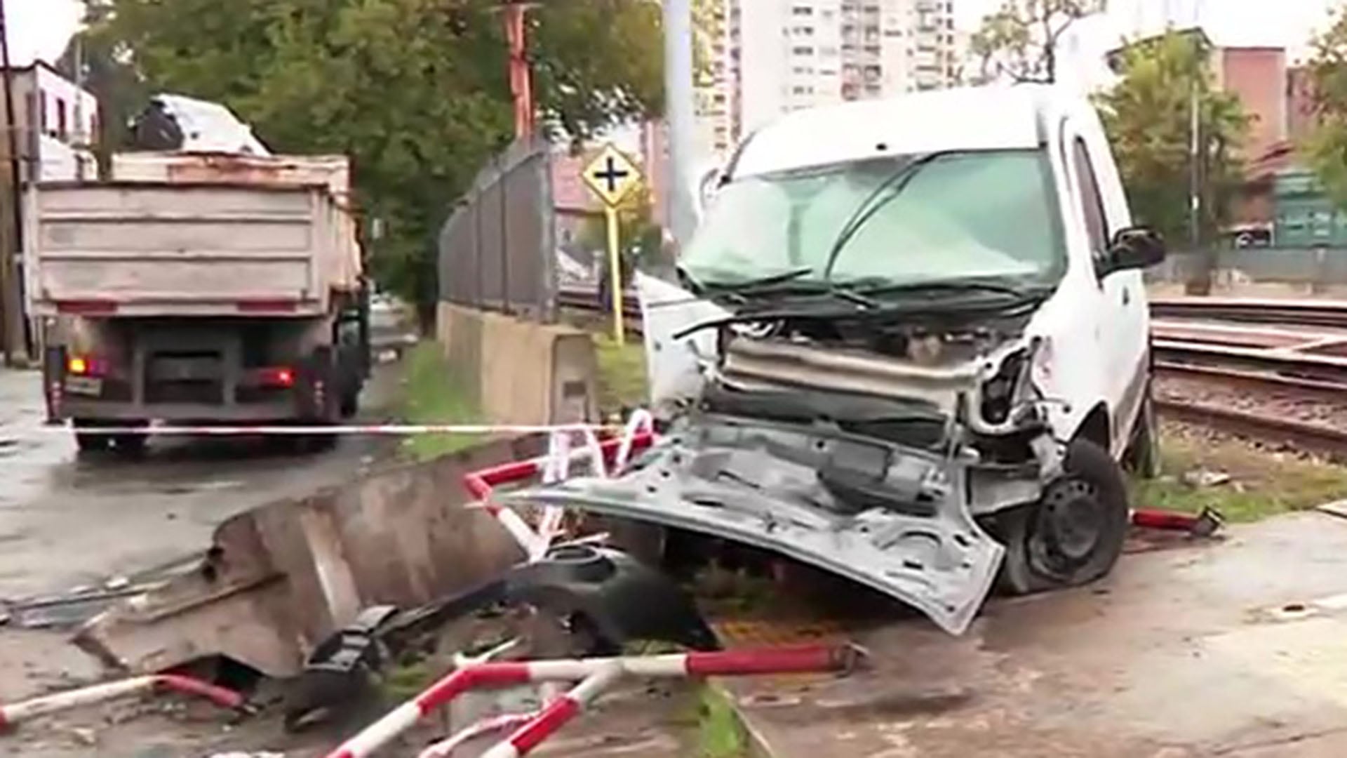 Una camioneta blanca gravemente dañada yace cerca de las vías del tren Sarmiento tras colisionar con una formación en Ramos Mejía. (Captura de video)
