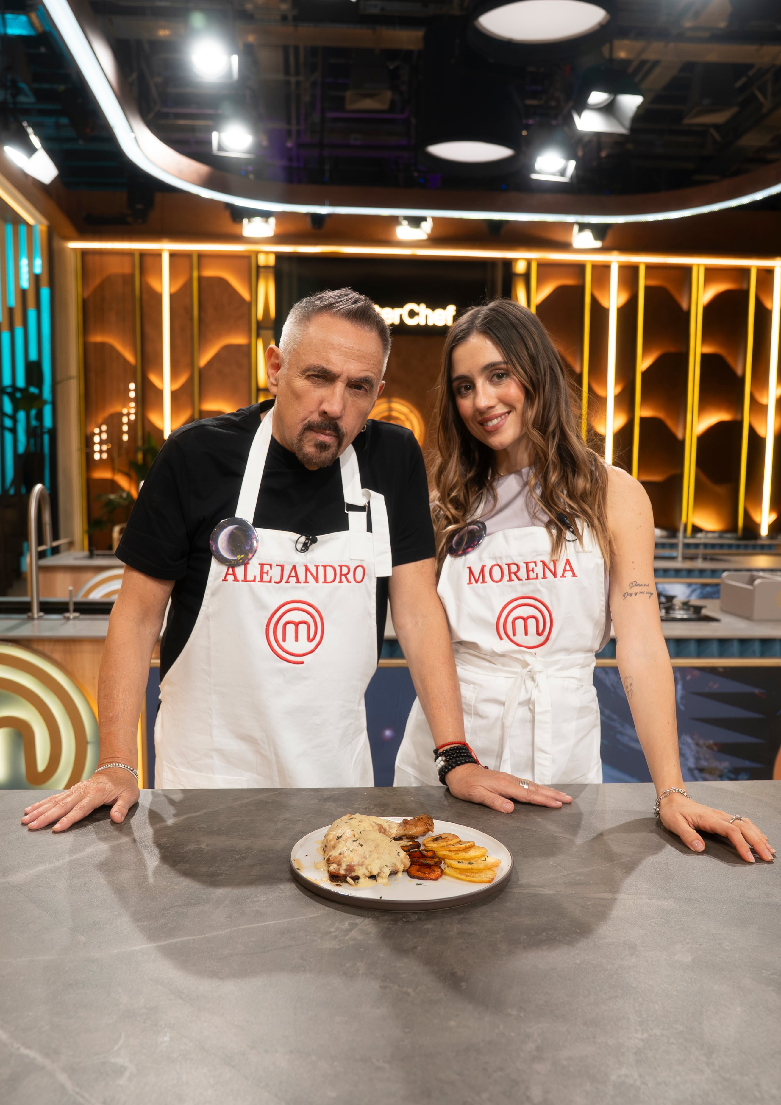 Alejandro Lerner y Morena Beltrán posan junto a un plato preparado en el estudio de televisión de MasterChef Celebrity.