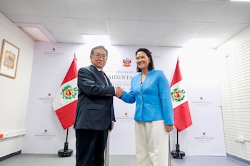 Dos personas, un hombre y una mujer, se dan la mano. Detrás hay dos banderas peruanas y un cartel con el texto 'Oficina de la Presidenta Electa Keiko Fujimori'