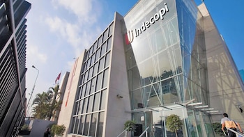 Fachada de un edificio moderno de cristal y piedra con el logotipo de Indecopi en la parte superior de la entrada