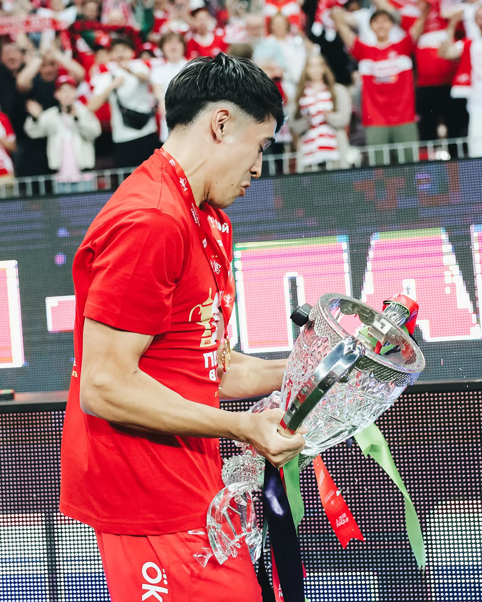 El futbolista Pablo Solari se muestra visiblemente afectado al sostener el trofeo roto mientras celebra un campeonato.