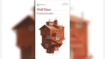 Cubierta de un libro blanco con el título 'Cortocircuito' y el autor 'Wolf Haas' en letras rojas y negras. Una casa de madera intrincada y vertical en el centro