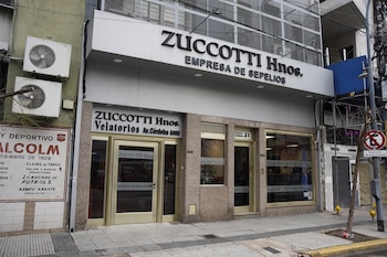 Fachada de la empresa Zuccotti Hnos. Velatorios en Avenida Córdoba 5080 con puertas de vidrio, carteles y dos aires acondicionados externos