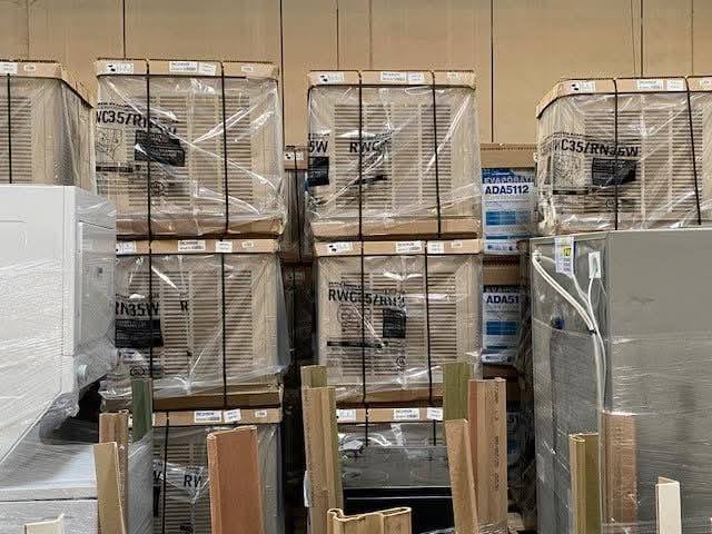 Se observa un almacén lleno de cajas, electrodomésticos y materiales de construcción apilados, relacionados con el Departamento del Sheriff del Condado de Los Ángeles.