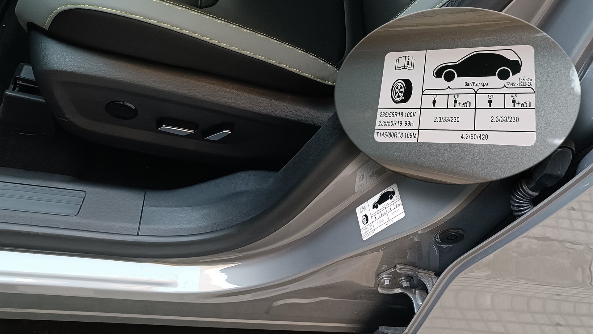 Una etiqueta informativa en el marco de la puerta de un automóvil detalla las presiones de neumáticos recomendadas según la carga y el tamaño de las ruedas, crucial para la seguridad y el rendimiento del vehículo.