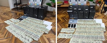 Gran cantidad de billetes de dólares estadounidenses, varias torres de computadora, una laptop y teléfonos celulares exhibidos sobre un piso de madera