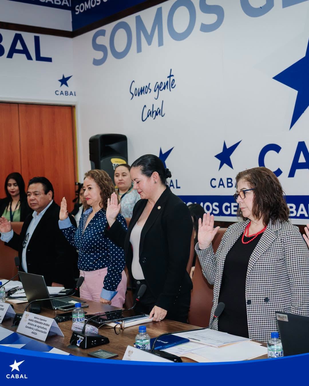 Un grupo de personas levanta la mano derecha durante una juramentación formal frente a un panel del partido Cabal. (Bancada CABAL )