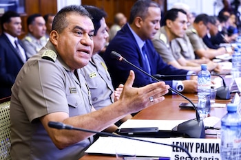 Primer plano de un hombre con uniforme militar, el Comandante General PNP Oscar Arriola, hablando y gesticulando en una mesa de reuniones con micrófonos