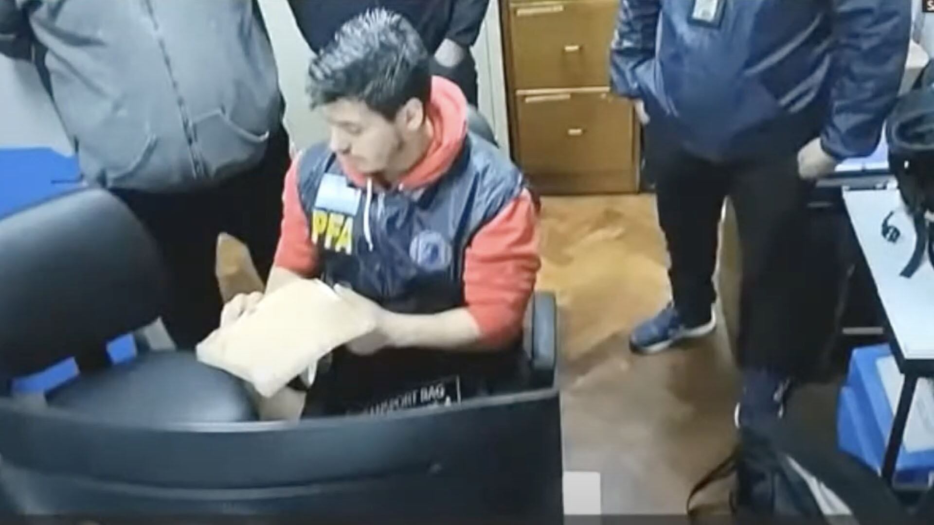 El perito de la PFA manipula el teléfono en el juzgado de Capuchetti.