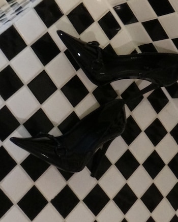 Los stilettos de charol negro con punta fina, del modelo Donna pump de Gucci, en un primer plano de detalle