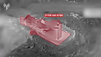Imagen aérea térmica en escala de grises mostrando estructuras terrestres, con una zona destacada en rojo y texto en hebreo. Un logo militar es visible en la esquina superior izquierda