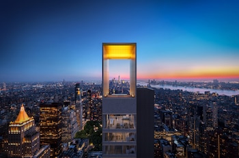 Vista aérea de un rascacielos con una abertura enmarcada en la cima, mostrando el horizonte de Nueva York al anochecer y el Flatiron Building