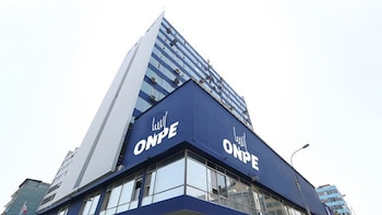 Edificio moderno de color azul y blanco con el logo y el nombre ONPE repetido en la fachada, y numerosas ventanas de vidrio bajo un cielo claro