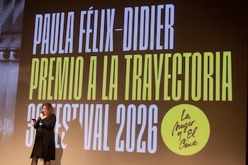Mercedes Morán sonríe luciendo un traje de dos piezas marrón claro mientras sostiene un diploma de reconocimiento y una estatuilla transparente