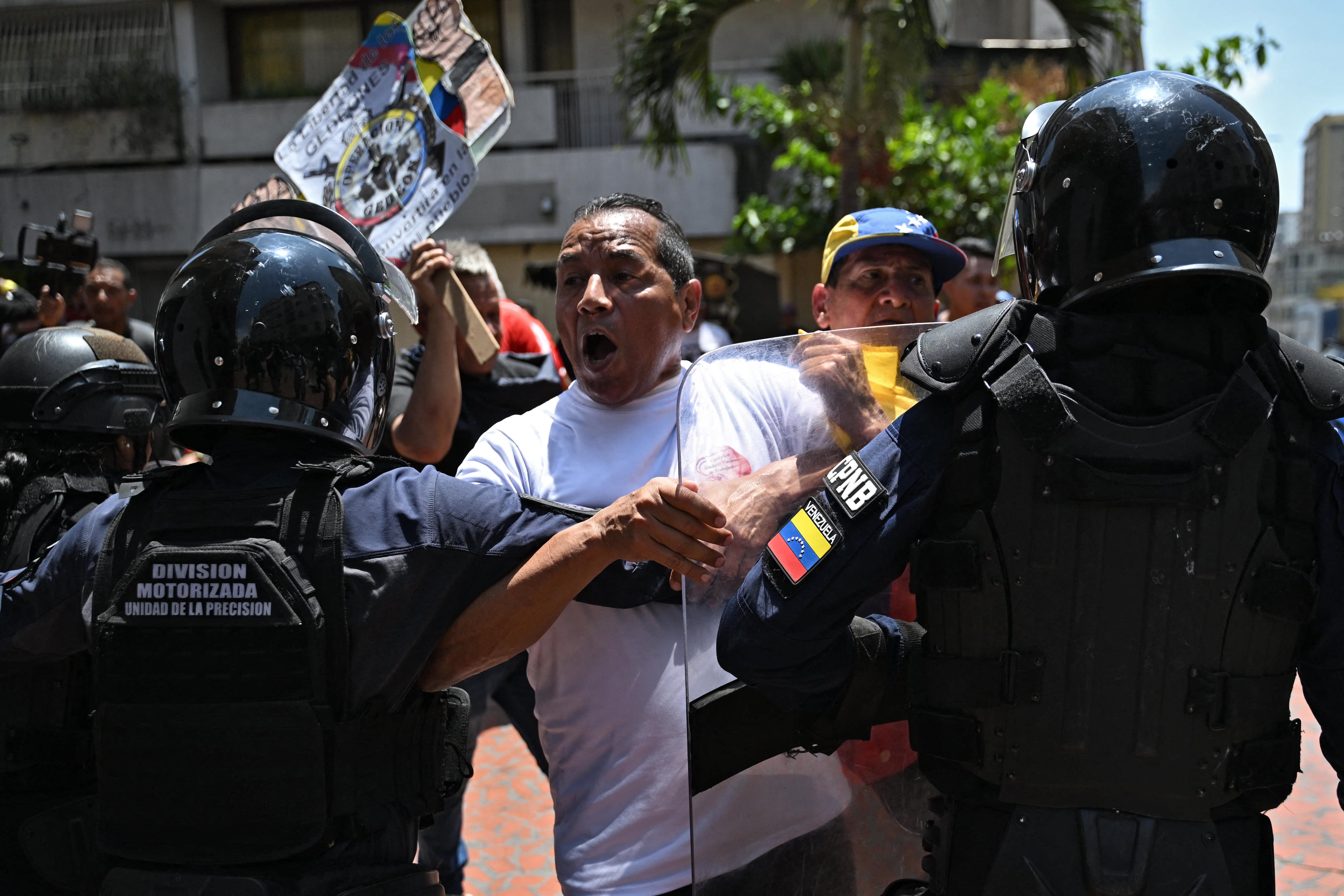 Un manifestante en Venezuela grita a un oficial de la Policía Nacional Bolivariana (CPNB) que sostiene un escudo, durante una tensa confrontación en las calles.