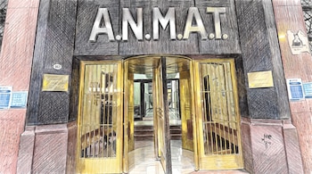 Fachada de edificio con el cartel ANMAT, una puerta giratoria dorada, dos puertas laterales doradas, el número 863 en la pared y afiches.