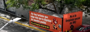 Vista aérea de vallas publicitarias anaranjadas en una calle de Monterrey con mensajes políticos. Un león futbolista y un puño en alto son visibles