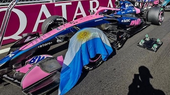 Automóvil de carreras azul y rosa con el número 43 y una bandera argentina sobre una de sus ruedas delanteras