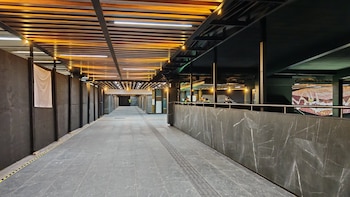 Pasillo amplio y moderno en la terminal Tasqueña del Metro CDMX. Tiene piso gris, techo de madera y luces. A la derecha, muro de mármol y mosaico