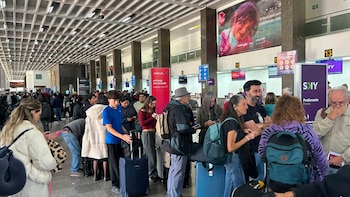 Multitud de pasajeros con equipajes hace fila en el interior de un aeropuerto, con mostradores de Avianca y Sky Airline, y un cartel de UNICEF en el fondo