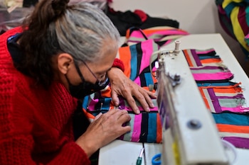 Una mujer trabaja confeccionando prendas