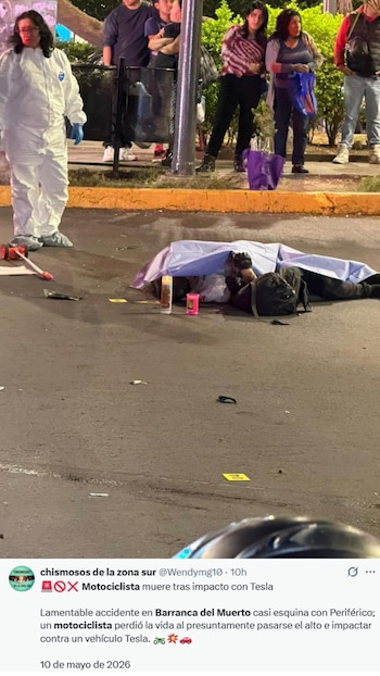En la noche, un perito forense en traje blanco junto a un cuerpo cubierto en el asfalto en una calle de CDMX, con curiosos observando y velas encendidas