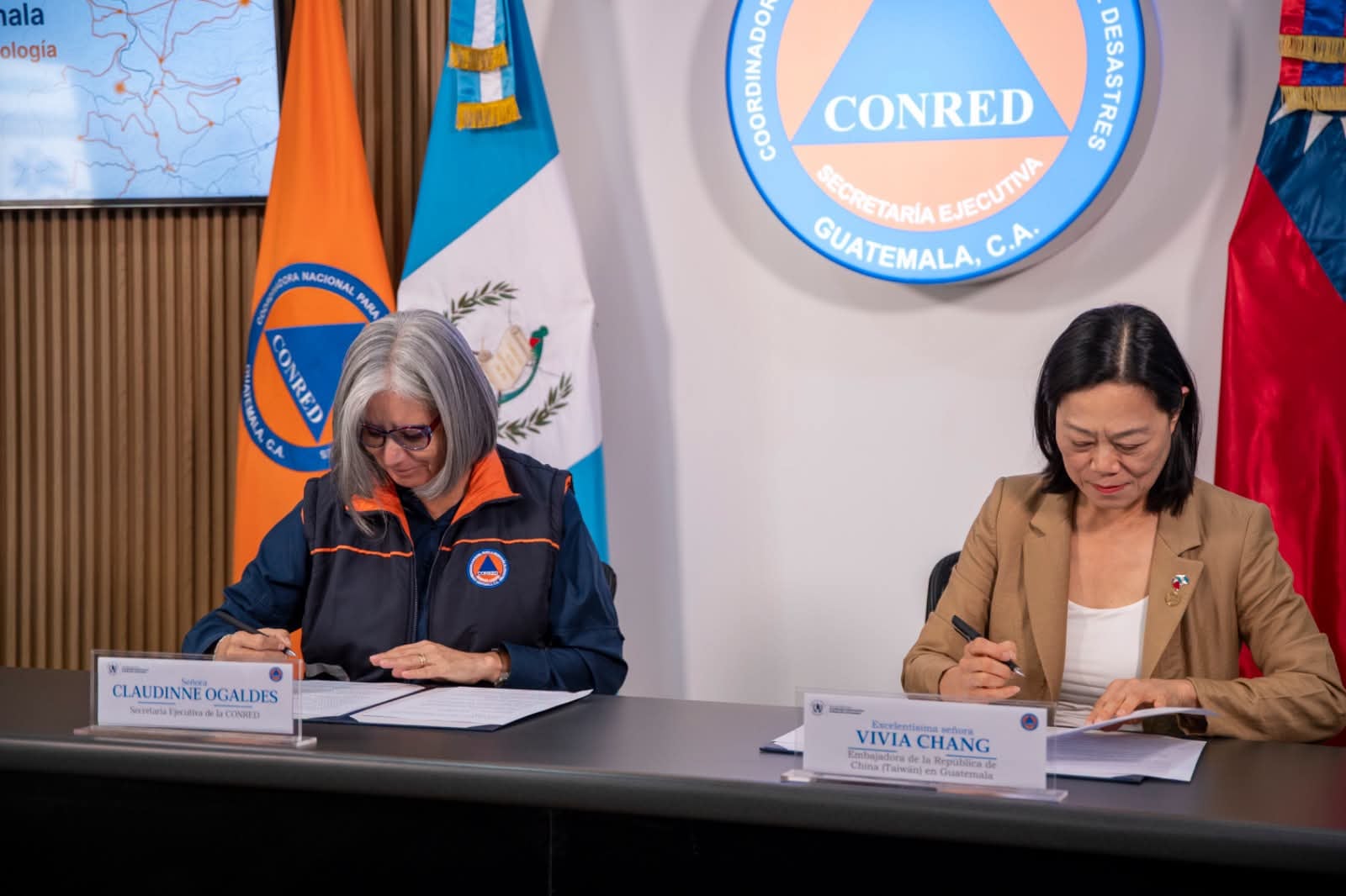 Claudinne Ogaldes, Secretaria Ejecutiva de CONRED, y Vivia Chang, Embajadora de Taiwán en Guatemala, firman un acuerdo. (Conred Guatemala)