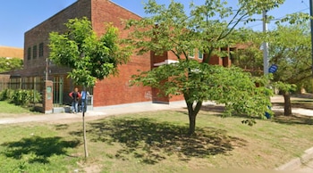 Exterior de la Escuela primaria Nº 1.337 Sylvestre Begnis en Rosario, un edificio de ladrillo con árboles y césped al frente bajo un cielo azul