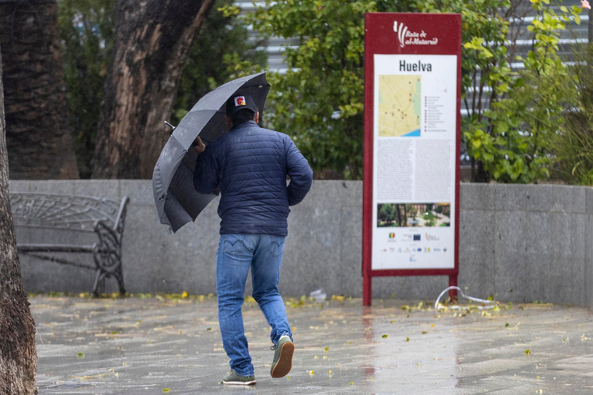 Un hombre camina con un paraguas en un día lluvioso frente a un cartel informativo de Huelva, con las calles mojadas por la precipitación (Imagen Ilustrativa Infobae) ( EFE/ David Arjona.)