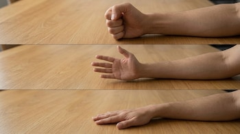 Tres imágenes de un brazo sobre una mesa de madera con la mano en puño, extendida de lado y plana con la palma hacia abajo