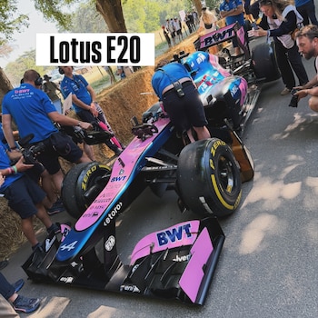 Monoplaza de carreras rosa y azul con logos BWT Alpine y número 44, rodeado por personal técnico y espectadores, con un cartel 'Lotus E20' sobrepuesto