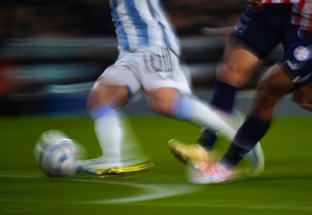 Hombre con camiseta de fútbol de Argentina con rayas celestes y blancas y el número diez, en movimiento borroso, sobre un fondo oscuro con tonos rojos