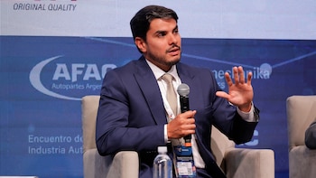 Primer plano de Igor Calvet, un hombre caucásico de barba oscura, con traje azul y corbata, hablando en un micrófono y gesticulando con la mano izquierda en un evento