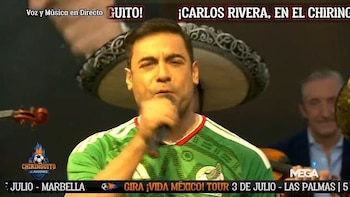 Hombre cantando en un micrófono, vestido con una camiseta verde, con un sombrero de mariachi y un violín al fondo. Logotipos y textos de televisión