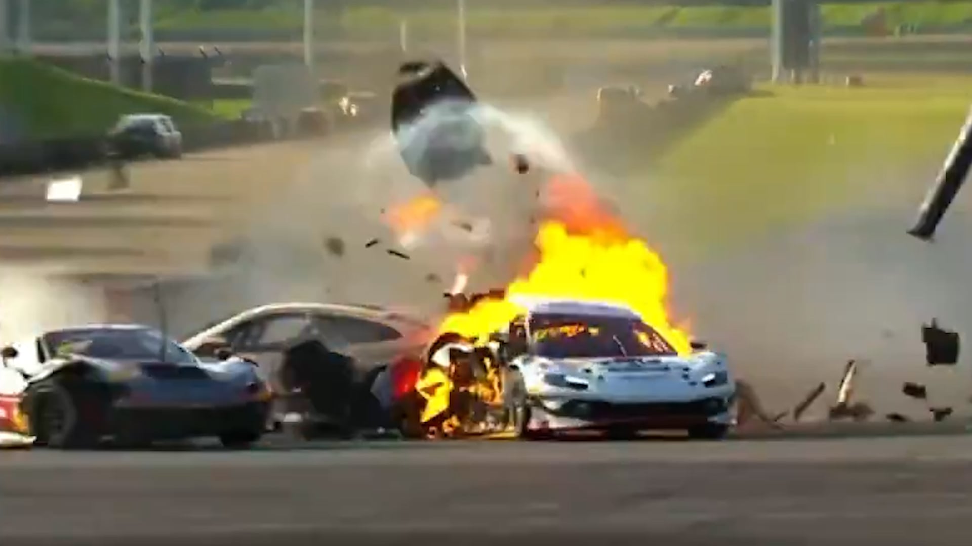 Varios automóviles de carreras sufren una colisión en la pista que genera un fuego intenso y la dispersión de piezas de los vehículos.