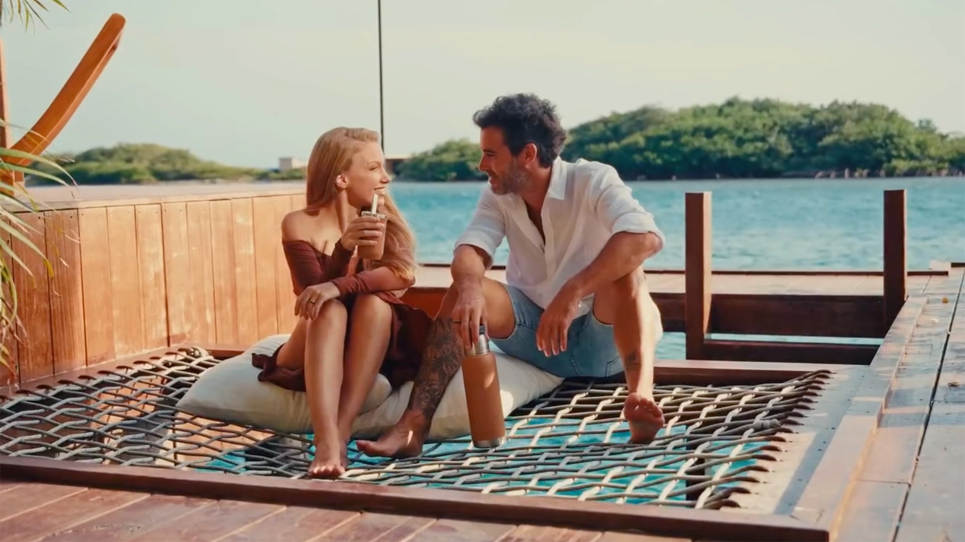 Relajados y cómplices, los recién casados comparten mates y risas sentados sobre la red suspendida, con el horizonte de Aruba como telón de fondo