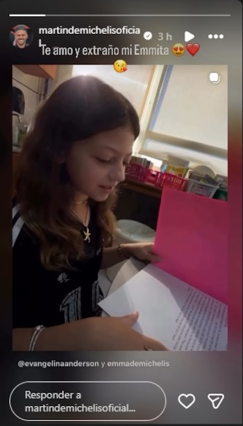 Una niña con cabello castaño, Emma Demichelis, sentada y mirando hacia abajo un papel blanco. Sus manos sostienen el papel y una carpeta rosa brillante