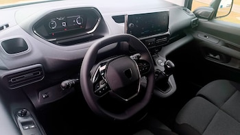 Interior de un vehículo con volante multifunción negro, panel de instrumentos digital, pantalla táctil central y palanca de cambios manual