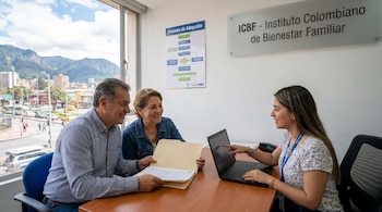 Una pareja sonriente examina documentos mientras una funcionaria del ICBF apunta a una pantalla de laptop. Al fondo, un diagrama de adopción y vistas de la ciudad.