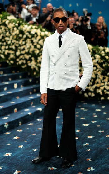 El cantante Pharrell Williams en la Met Gala, con un conjunto bicolor compuesto por una chaqueta blanca cruzada de textura granulada, con solapas anchas y seis botones metálicos visibles, sobre una camisa blanca clásica y corbata negra estrecha /REUTERS/Mario Anzuoni